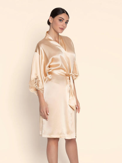Woman wearing a beige satin robe against a plain background