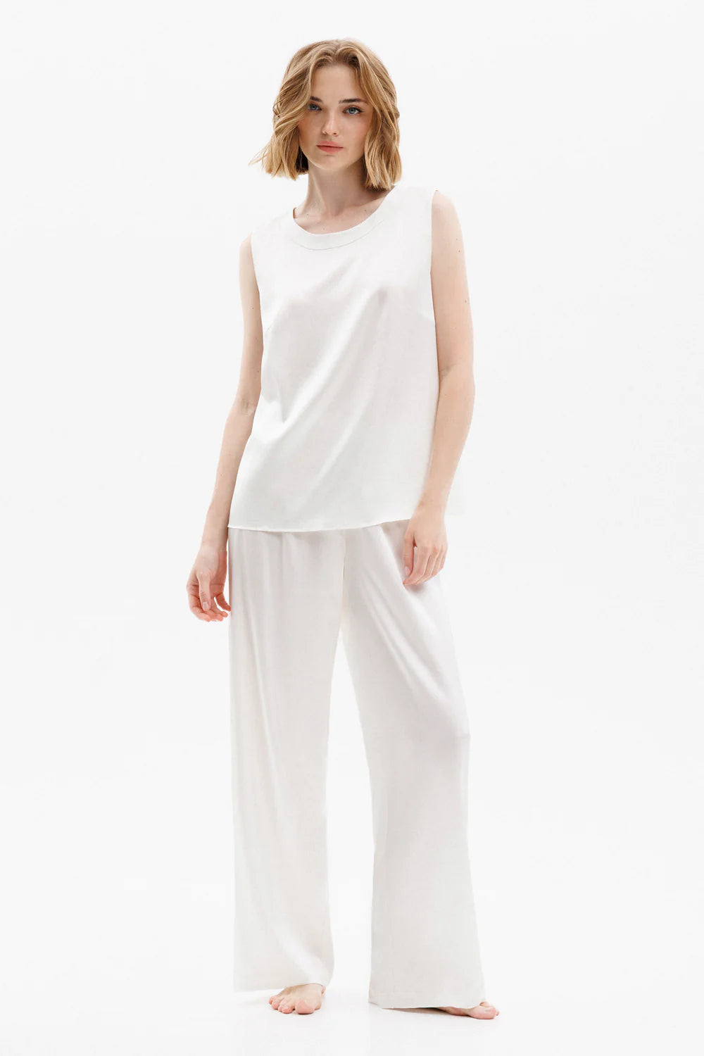Woman wearing a white silk sleeveless top and pants (sold separately) showing the front full look
