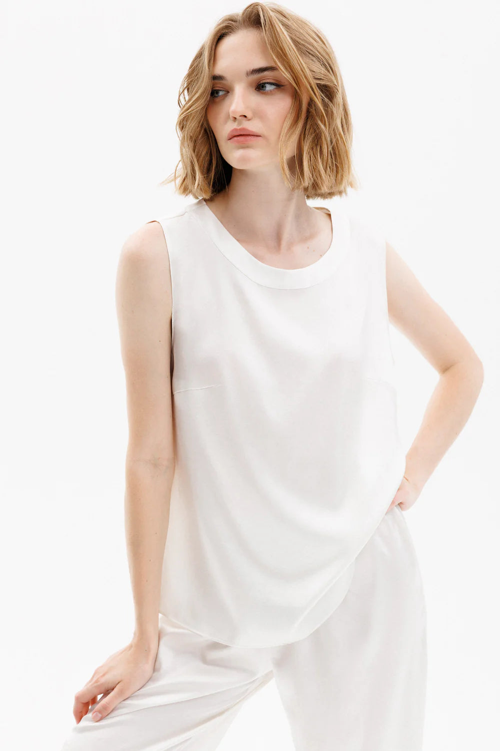 Woman wearing a white silk sleeveless top and pants (sold separately)