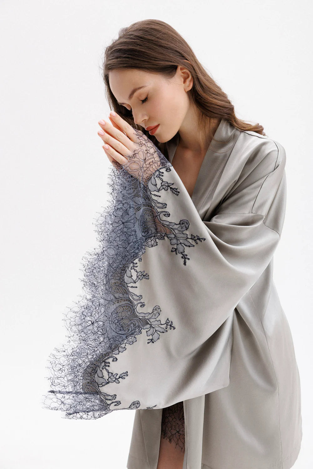Woman wearing a gray silk robe with Leavers Lace sleeves showing the elegance of the sleaves and beauty of the delicate anthracite lace
