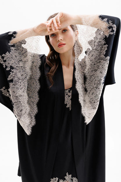 Woman wearing a black short silk robe with Leavers Lace sleeves showing the elegance of the sleaves