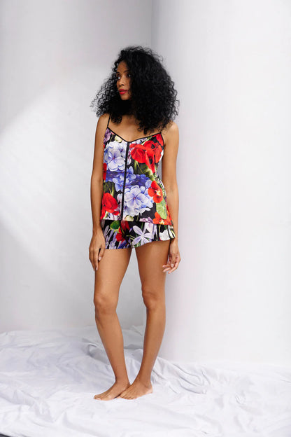 Woman wearing a colorful floral silk set of camisole and shorts. Showing the front full look.